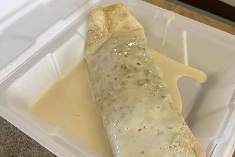 A burrito grande covered in cheese dip