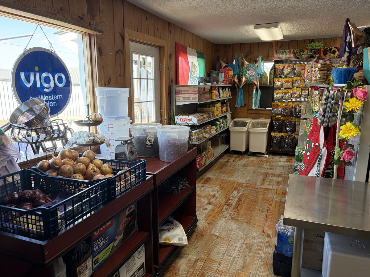 Onions and garlic on the counter beside tubs of dried chiles